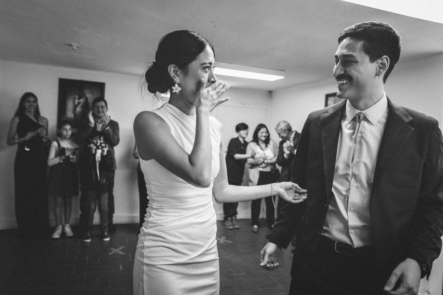 A candid black and white photo showing an animated conversation at an indoor event.
