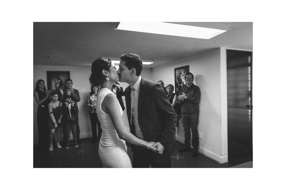 A black and white photo capturing a dance in an indoor space with onlookers.