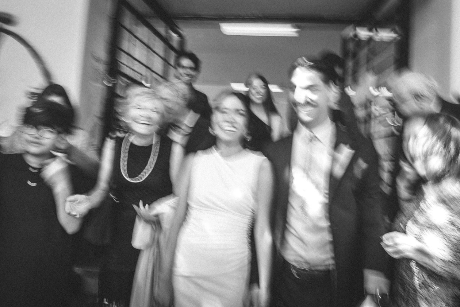 Black and white photo showing a group sharing genuine laughter and smiles together indoors.