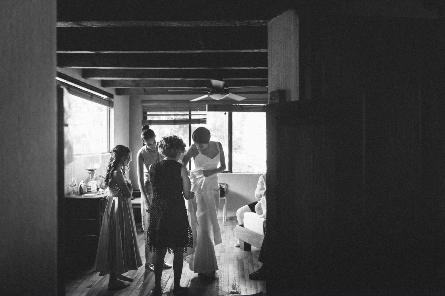 A black and white photo shows silhouetted figures standing in a doorway with dramatic backlighting.