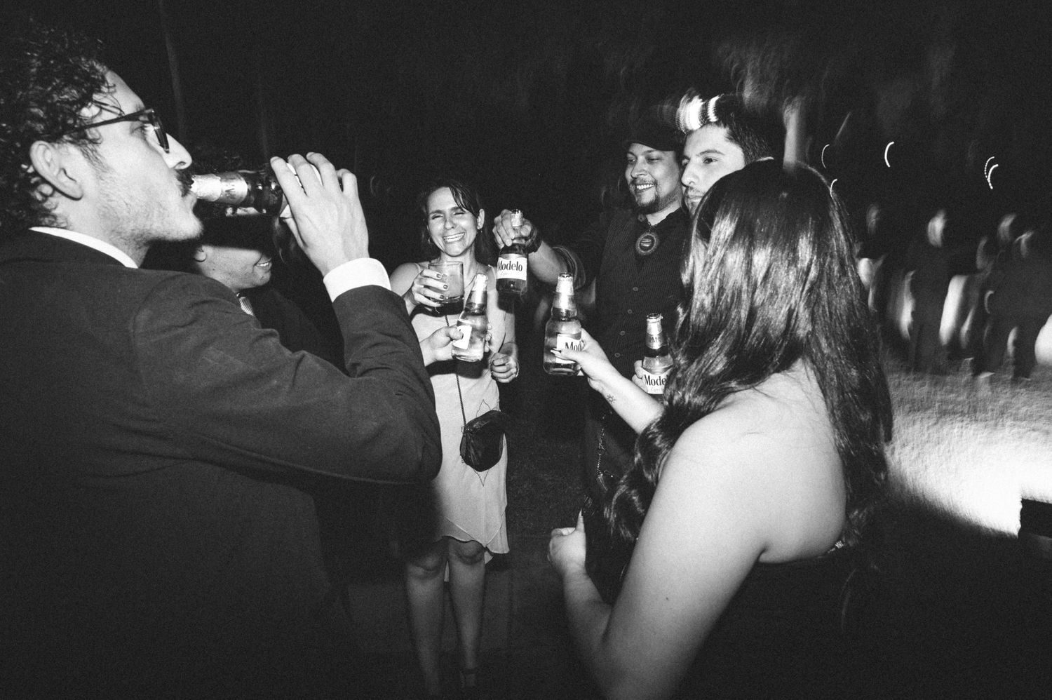 Black and white photo of people socializing and drinking at a party or nightclub gathering.
