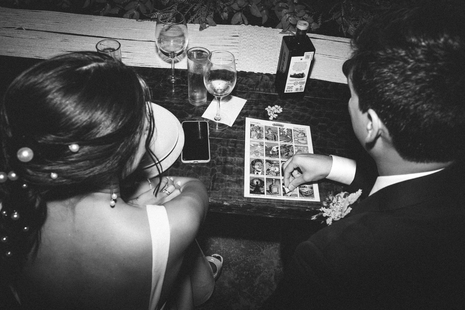A sequence of black and white film strip frames showing a dark interior scene with figures gathered around a table.