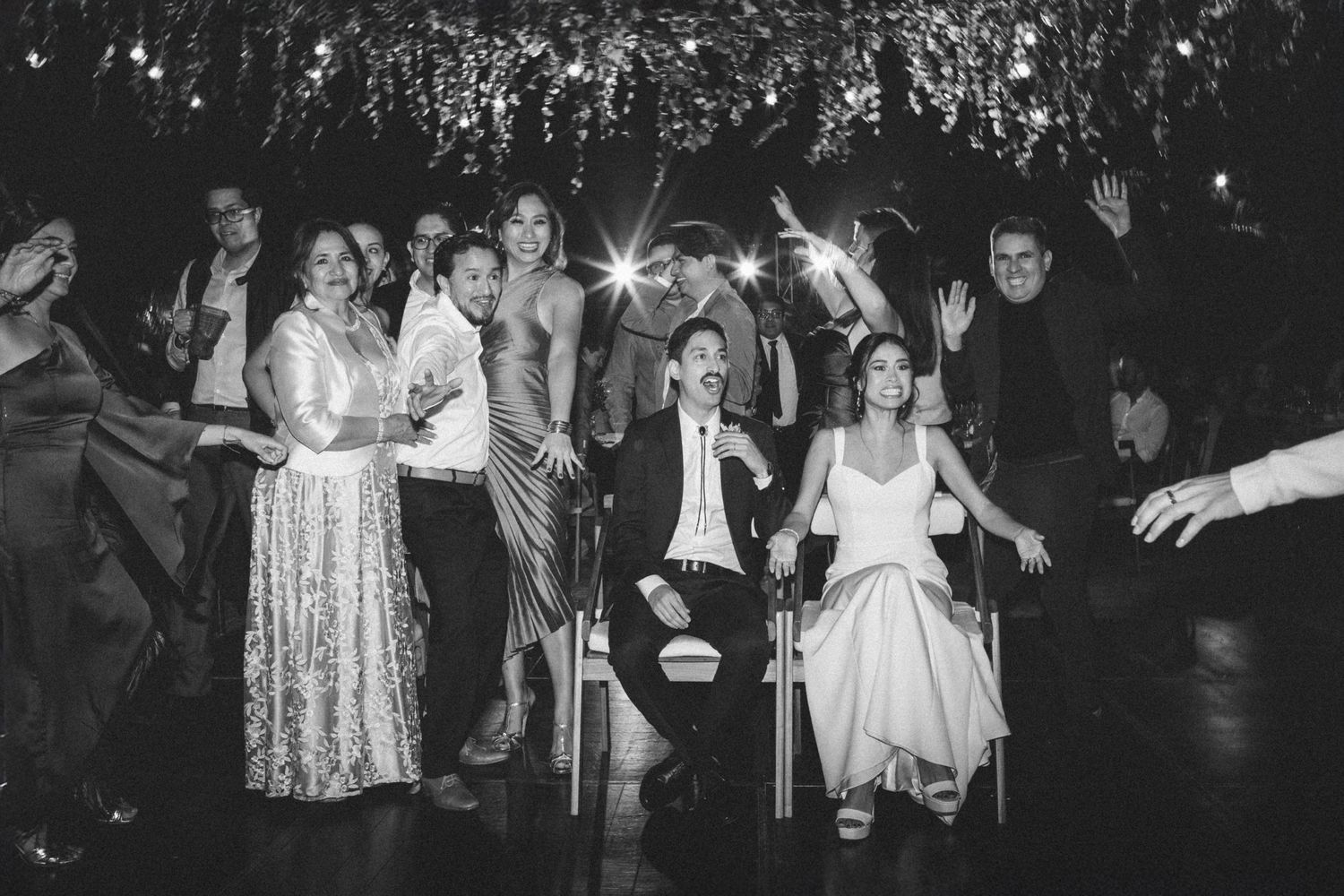 Wedding guests dancing and celebrating with sparklers on a dark dance floor during a wedding reception celebration.