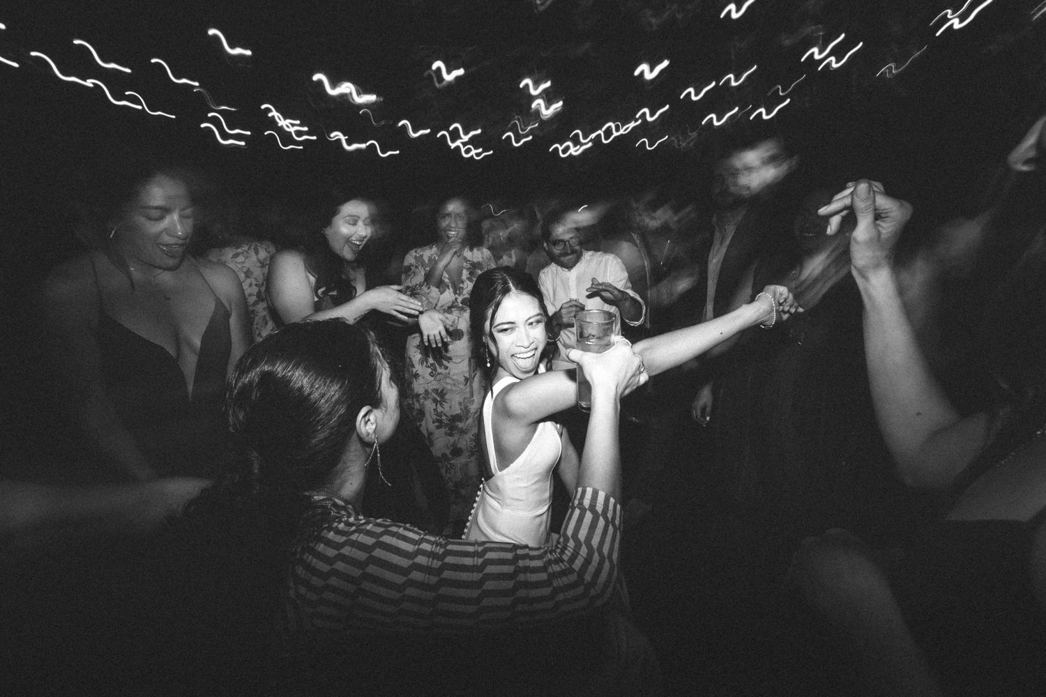 Black and white photo of people dancing and moving energetically in a crowded nightclub.
