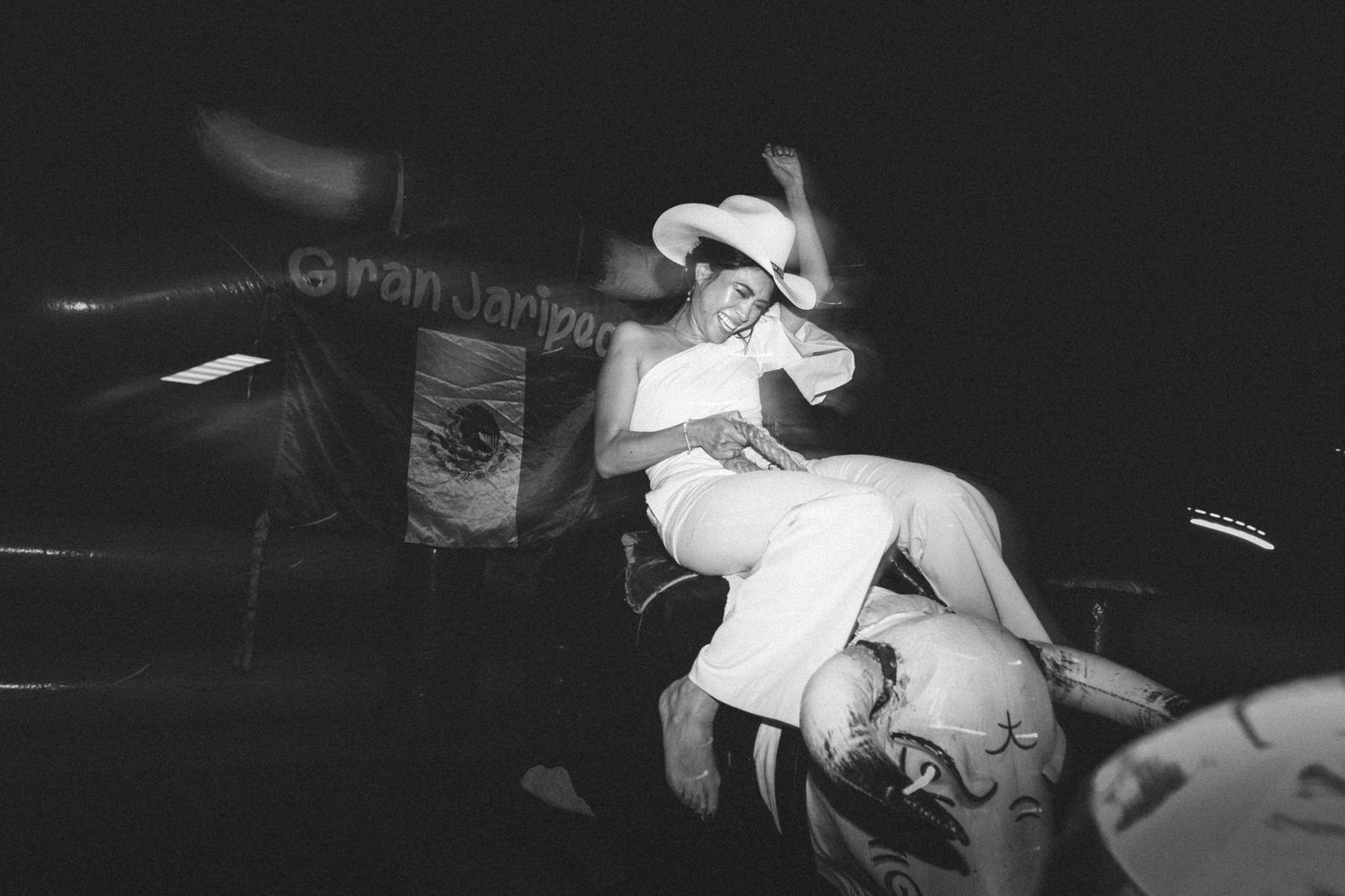A performer in white attire dances energetically during a dark nightclub performance captured in black and white photography.