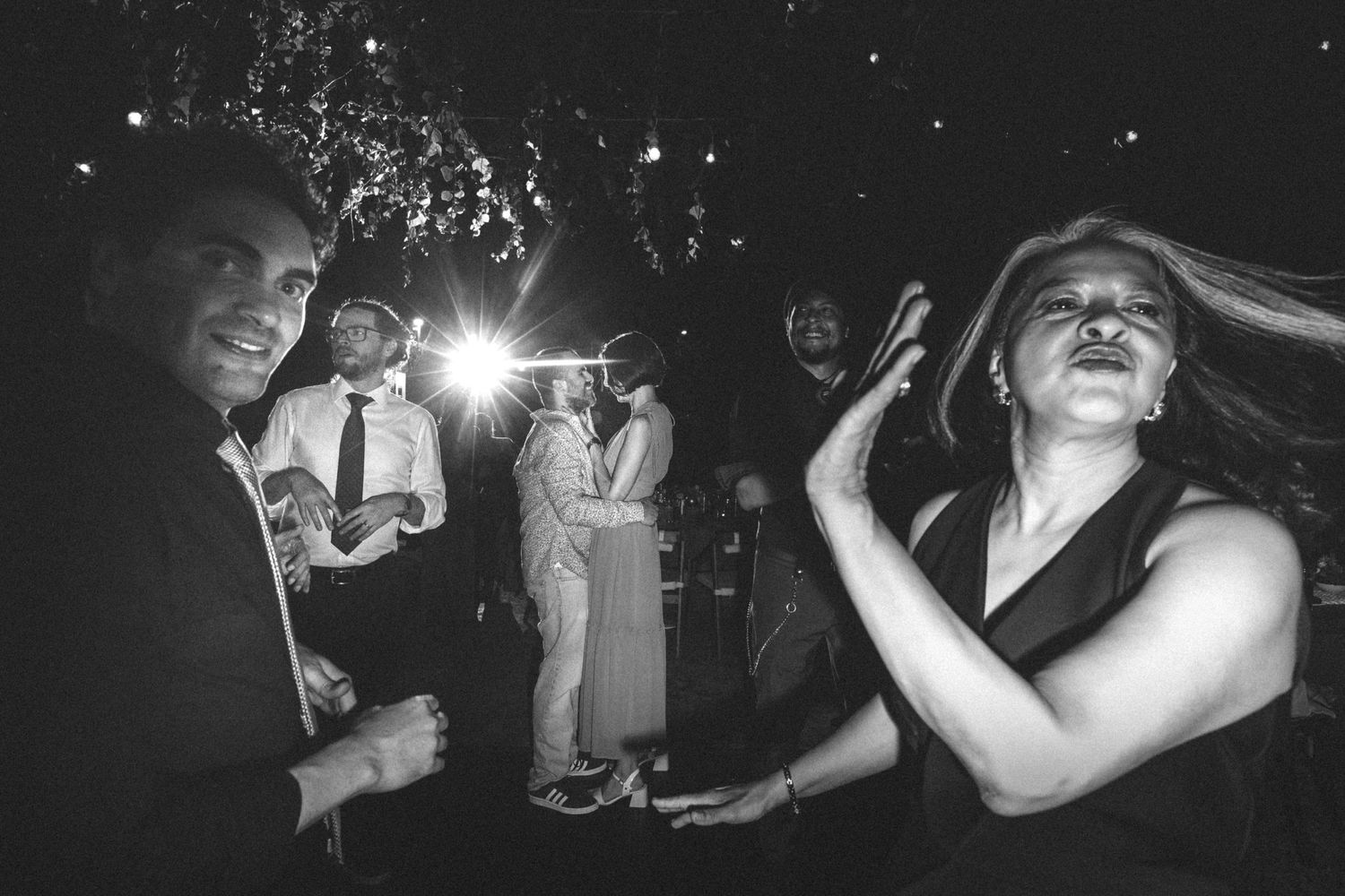 People dance and celebrate in black and white photos capturing lively nightclub moments at a party.
