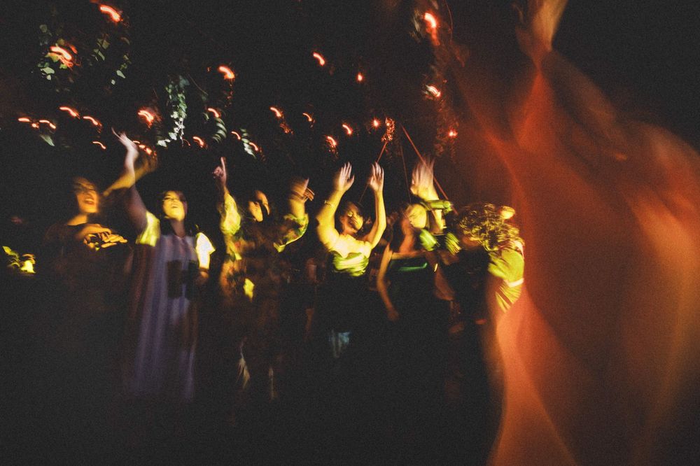 Silhouetted crowd enjoying a concert with colorful stage lighting creating an atmospheric orange and yellow glow.
