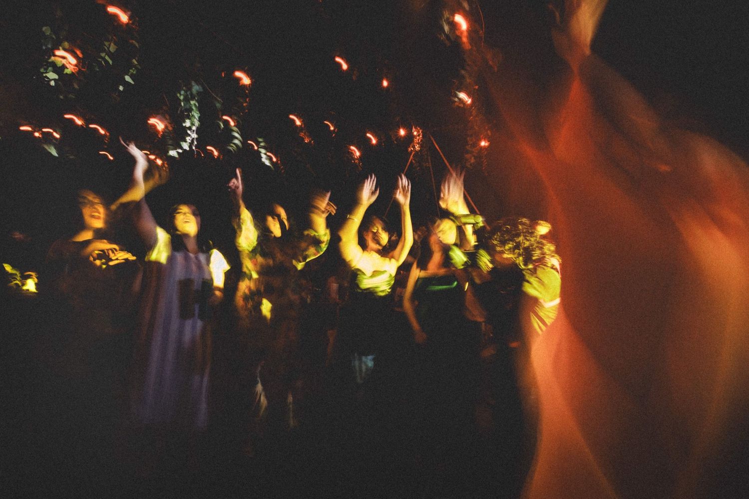 Silhouetted crowd enjoying a concert with colorful stage lighting creating an atmospheric orange and yellow glow.