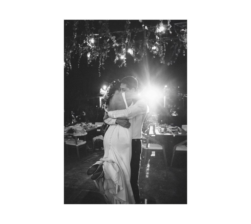 A couple dances together under dramatic lighting at an evening wedding reception in black and white.