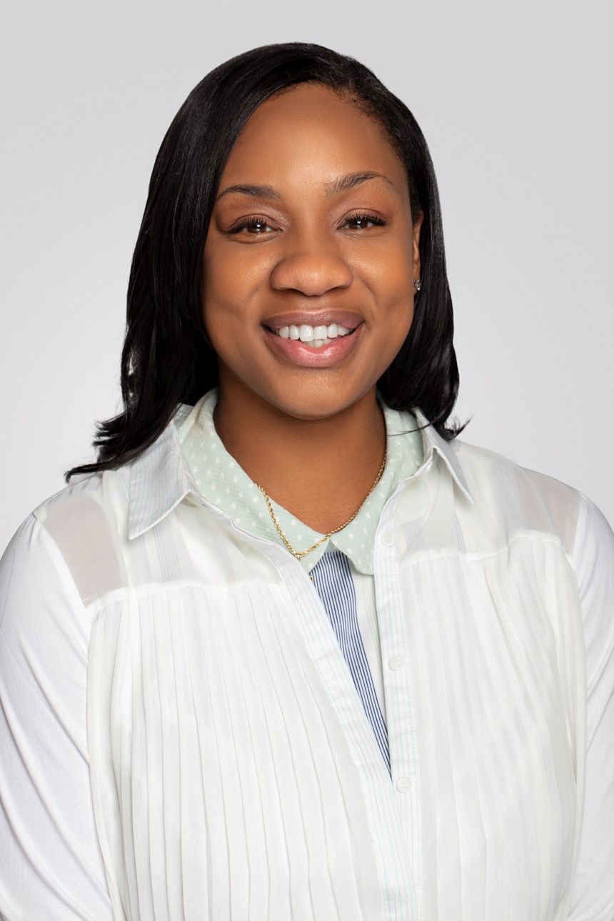 Professional headshot of a person wearing a white button-up shirt against a light gray background.