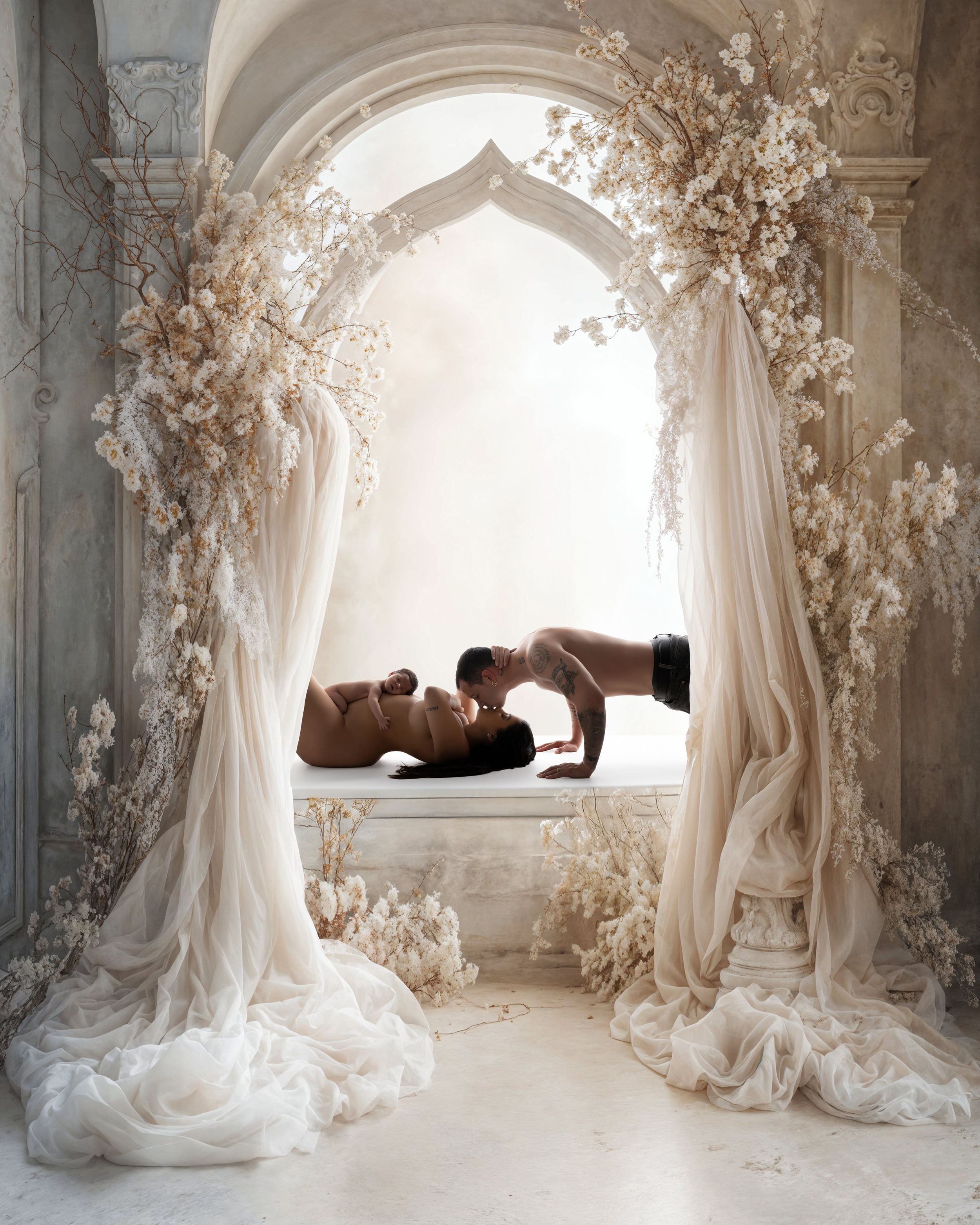 Elegant artistic backdrop features flowing white drapes and floral arrangements creating a romantic ethereal arch.