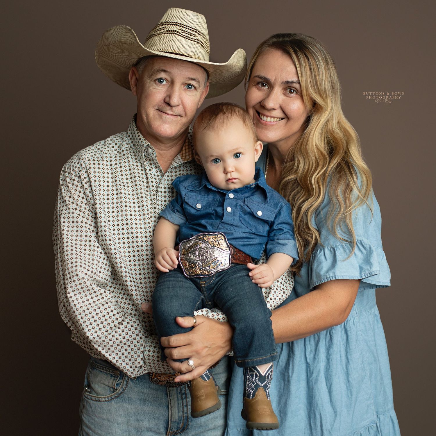 Family photography Ipswich and Brisbane – parents with baby in coordinating blue and white outfits, professional studio portraits at Buttons