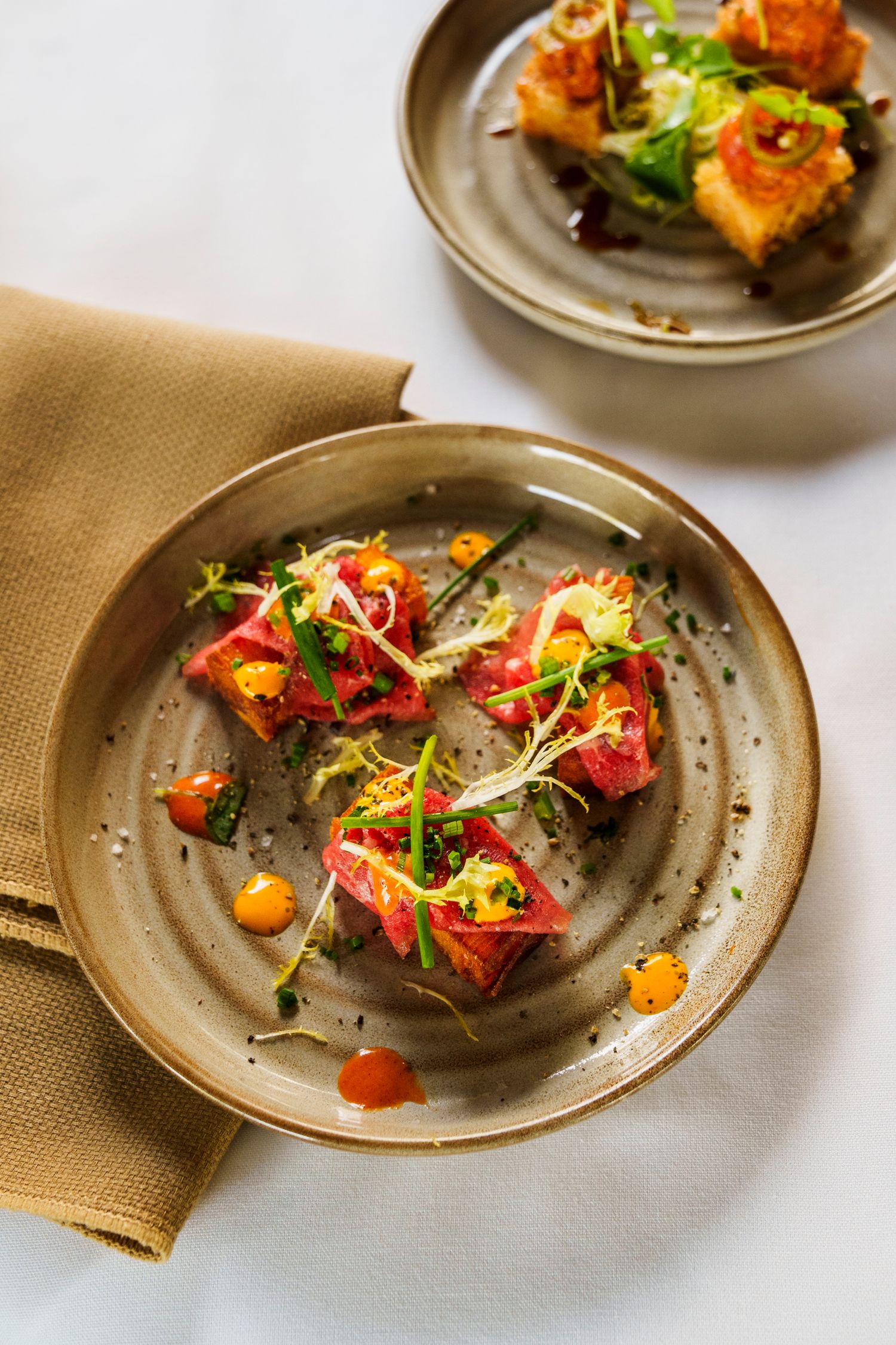 Beautifully plated gourmet dish with microgreens and colorful garnishes on a rustic ceramic plate.