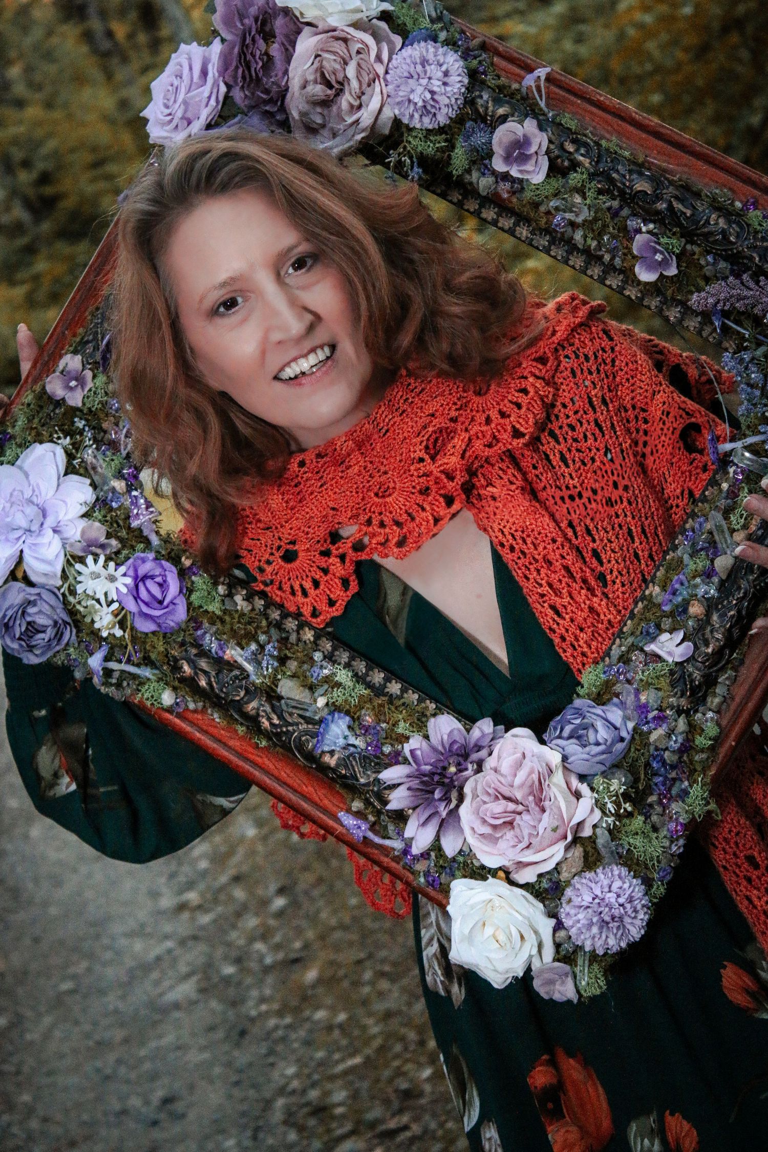 Fashion portrait featuring a orange crochet shawl and purple floral arrangements in a rustic wooden frame setting.