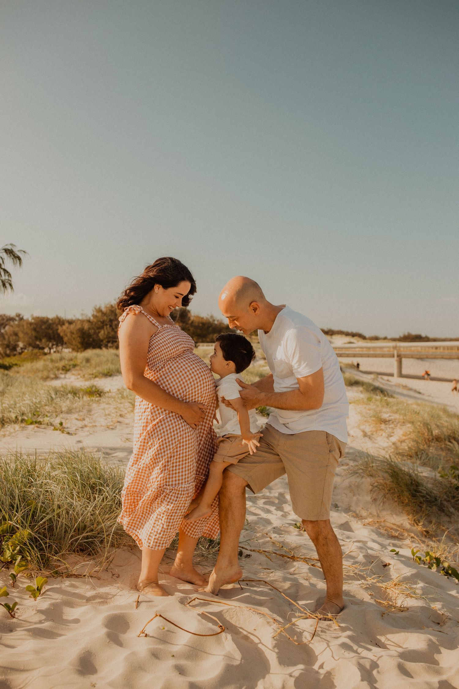 A couple shares playful moments on sandy beach dunes at sunset in a series of romantic candid photographs.