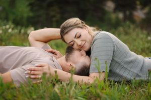 A couple lying together in a grassy meadow looking peaceful and romantic.