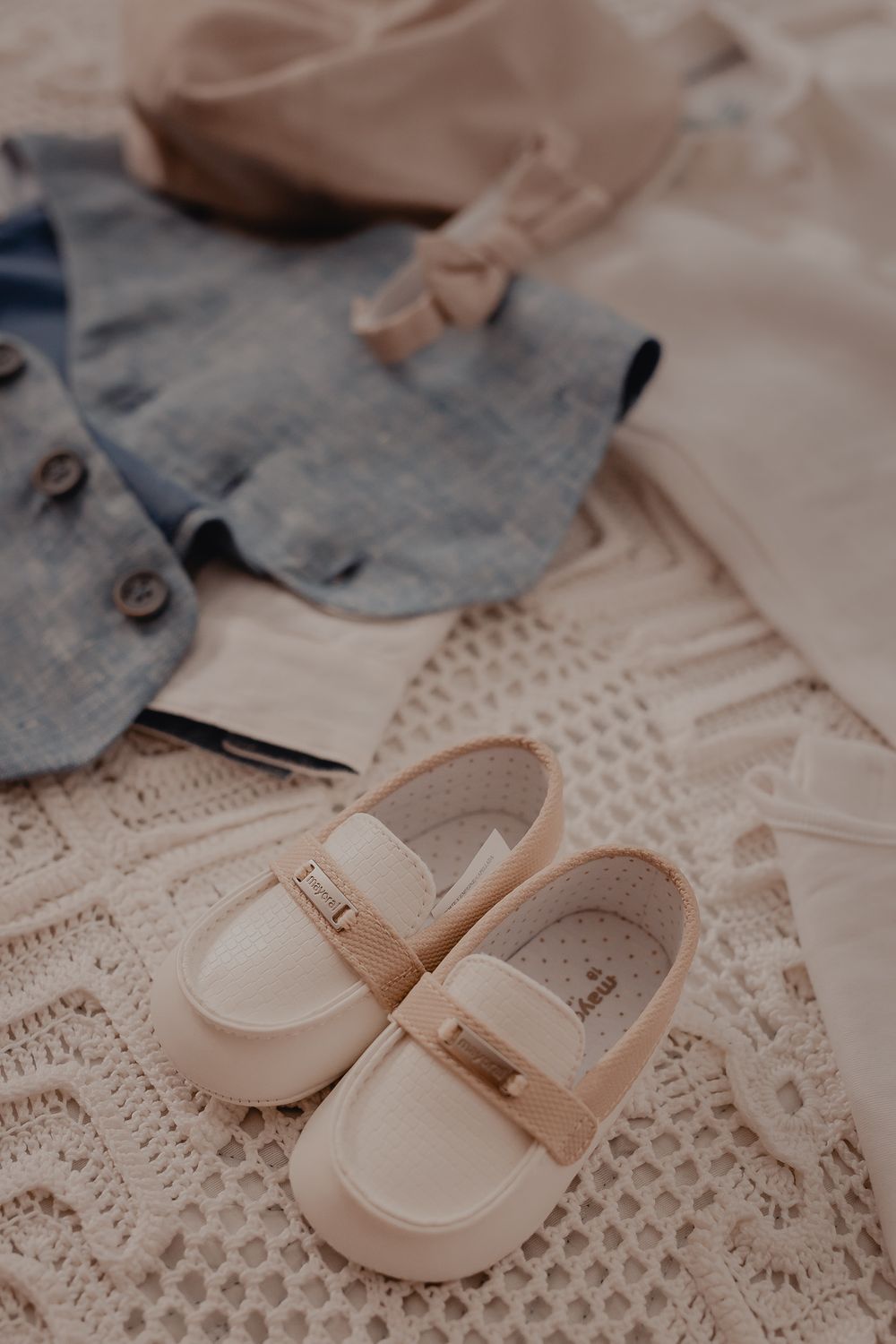 Delicate baby shoes displayed on lace fabric with soft lighting.