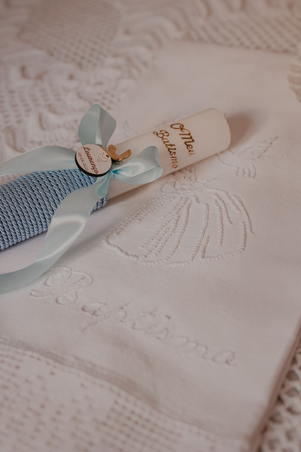 White baptismal gown with delicate embroidery and blue ribbon details.