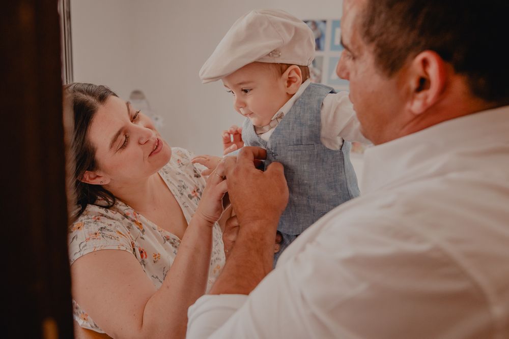 Family sharing playful moment with baby wearing light gray cap.