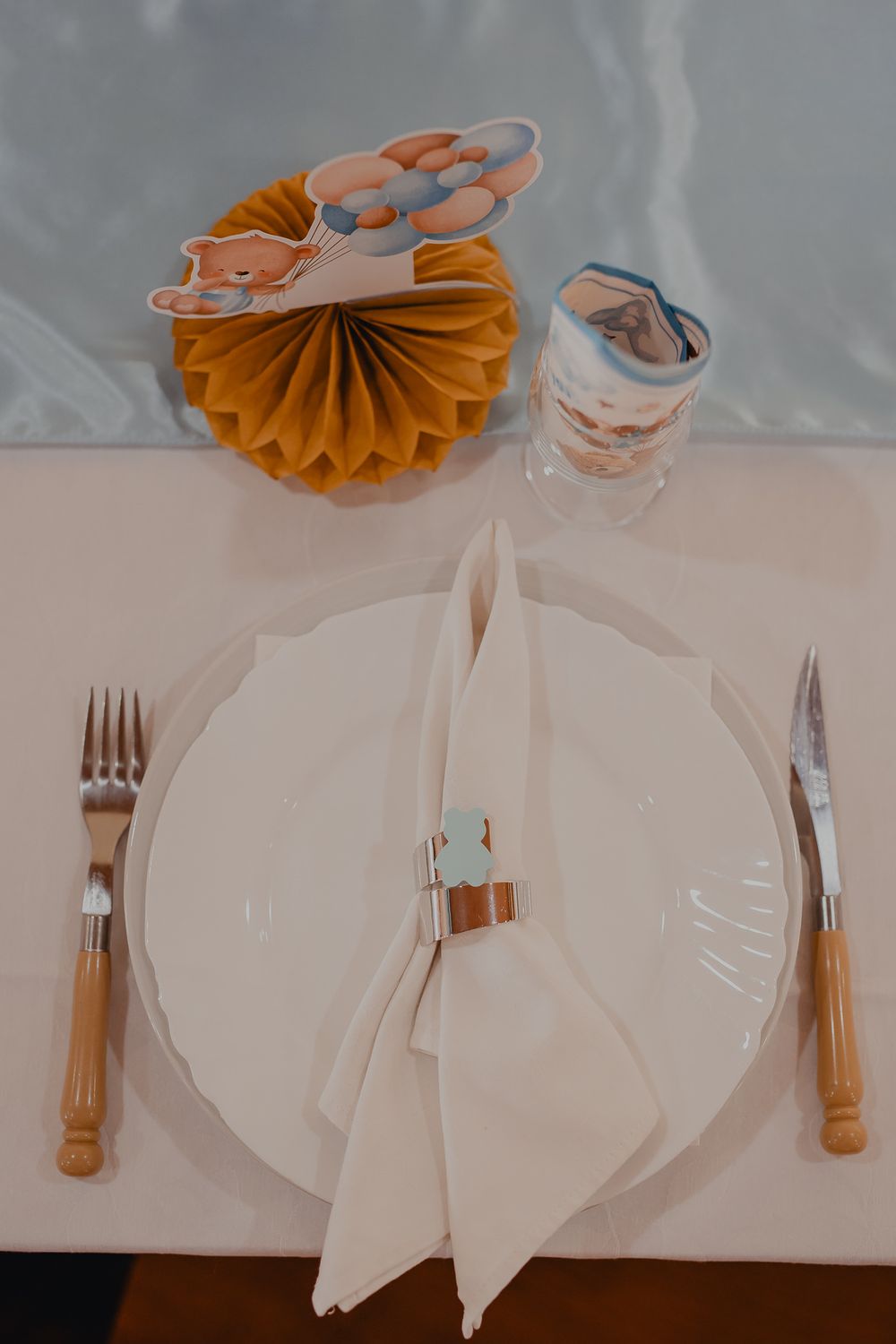 Table setting with white napkins and orange paper decorations.
