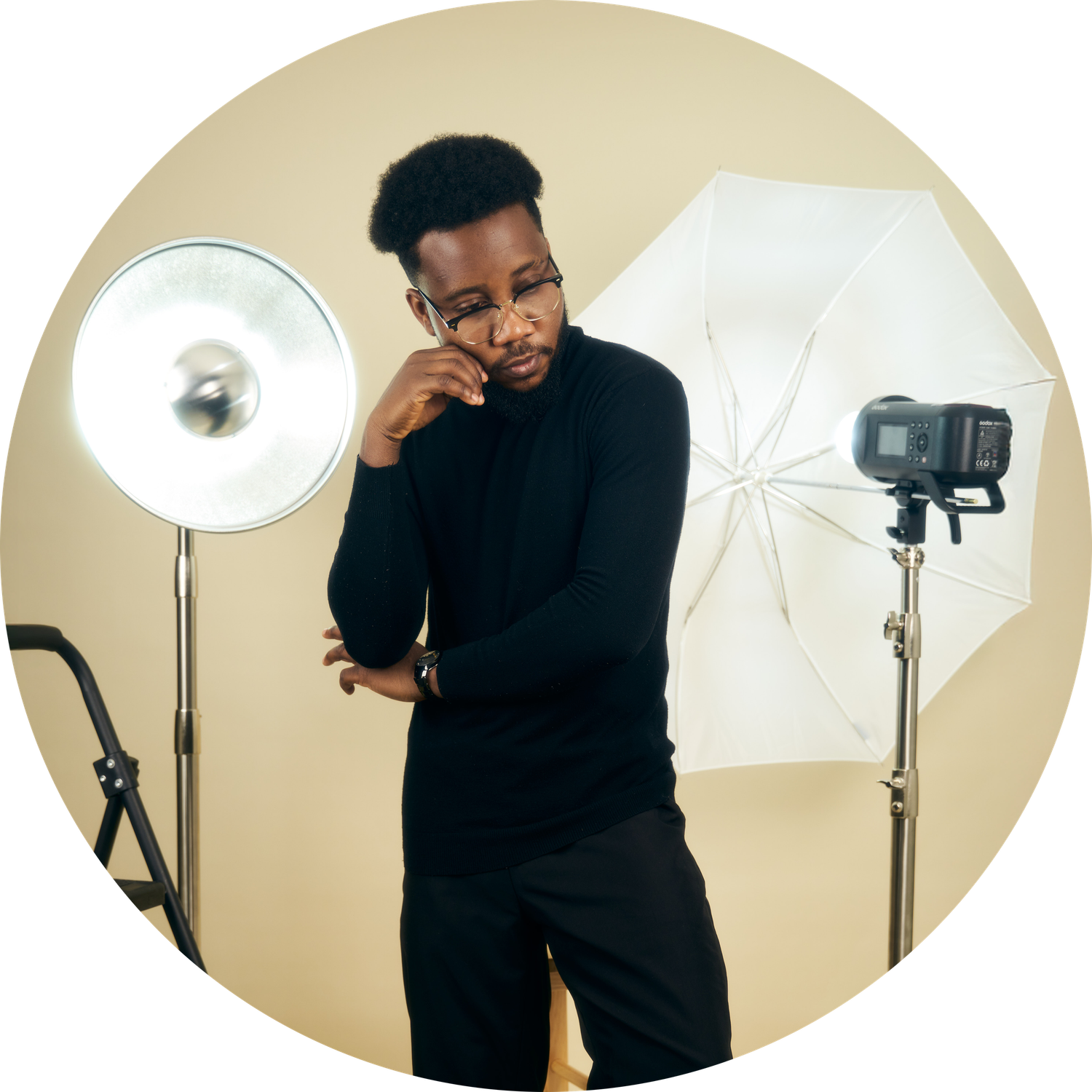 Photographer works with studio lighting equipment against beige backdrop.