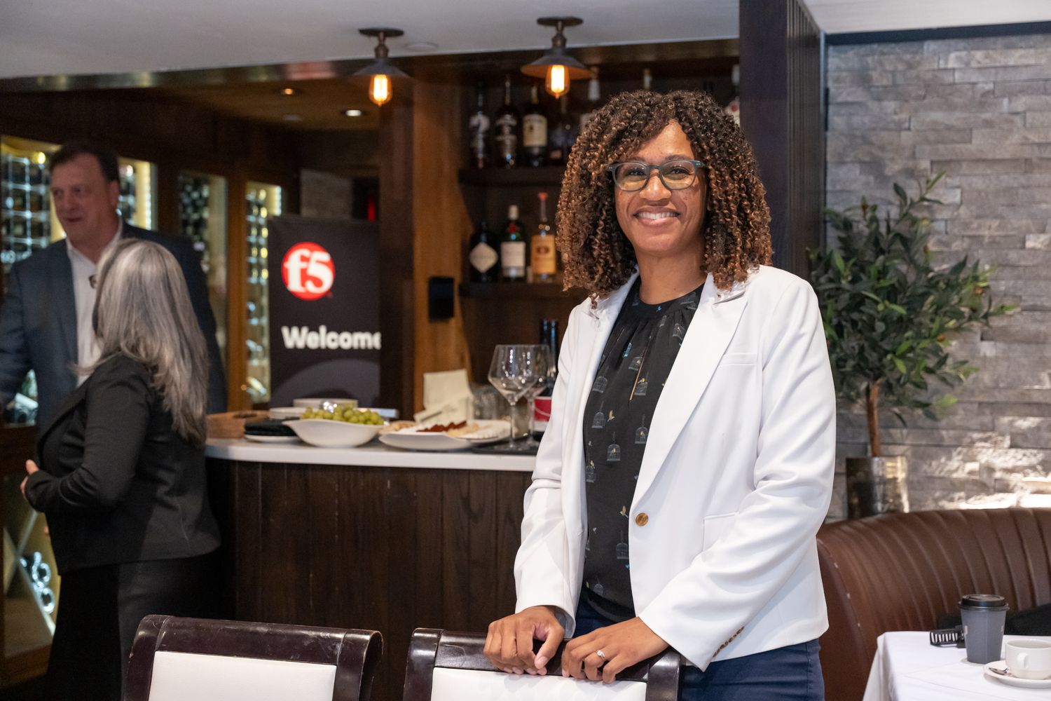 Professional event staff in white blazers greet guests at an upscale venue entrance.