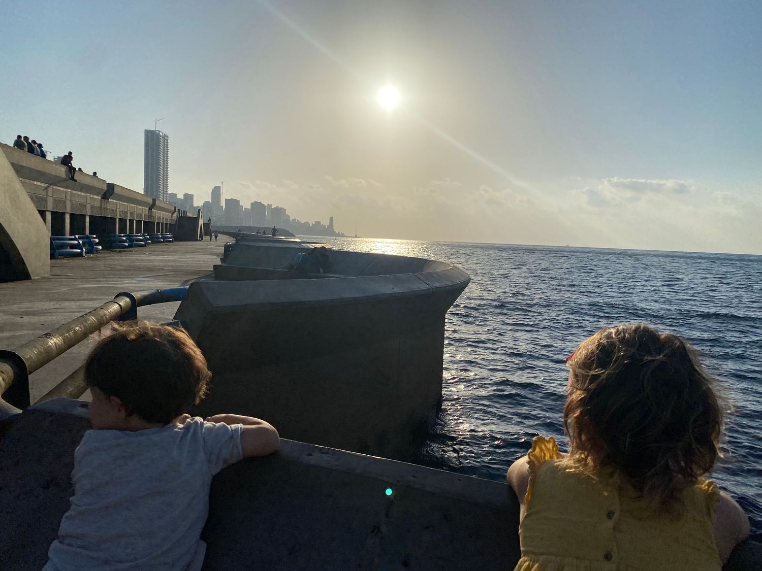 People viewing the ocean and Havana skyline from the Malecon seawall during a sunny afternoon in Cuba.