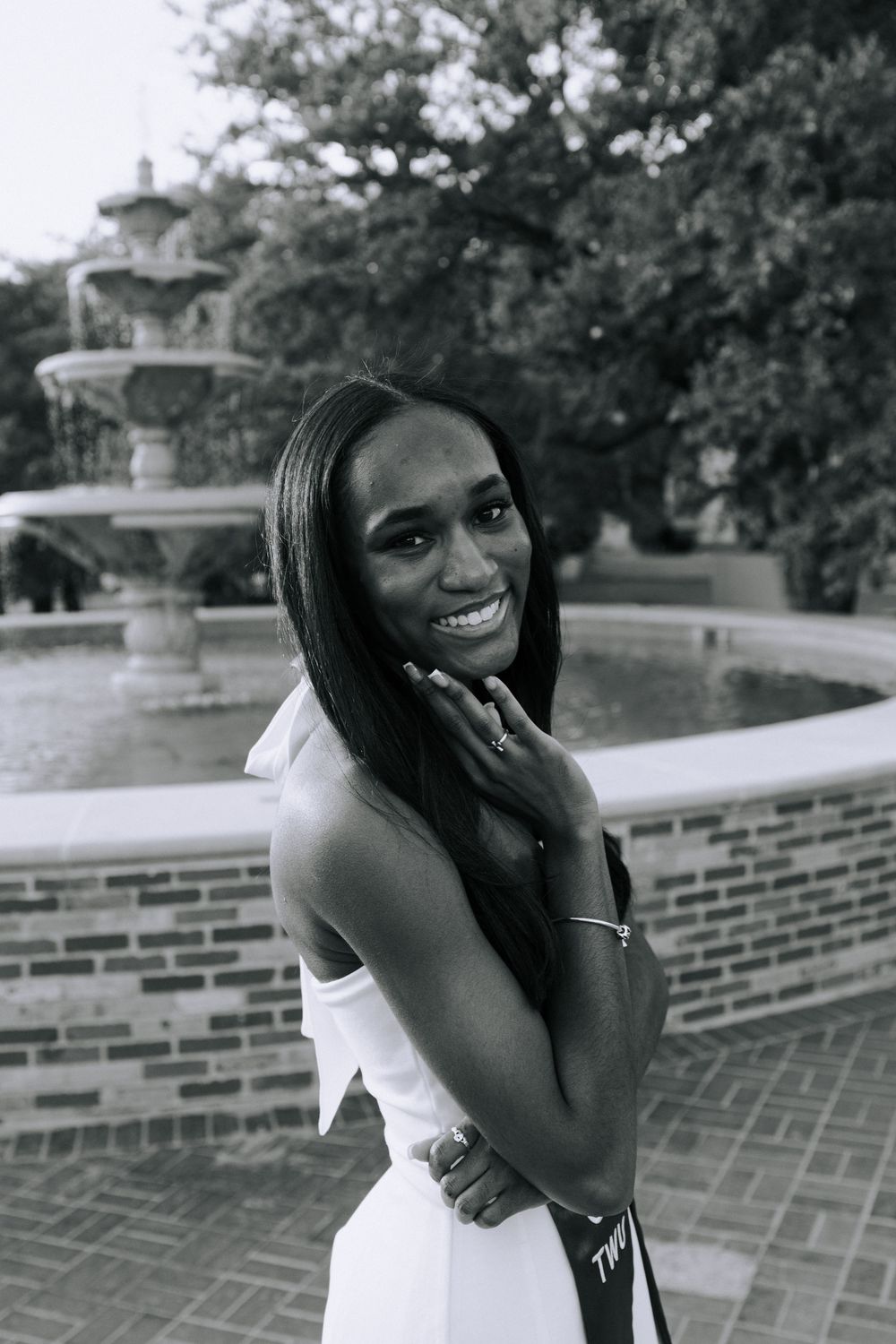 Graduate in formal attire poses expressively on brick steps during photo session.
