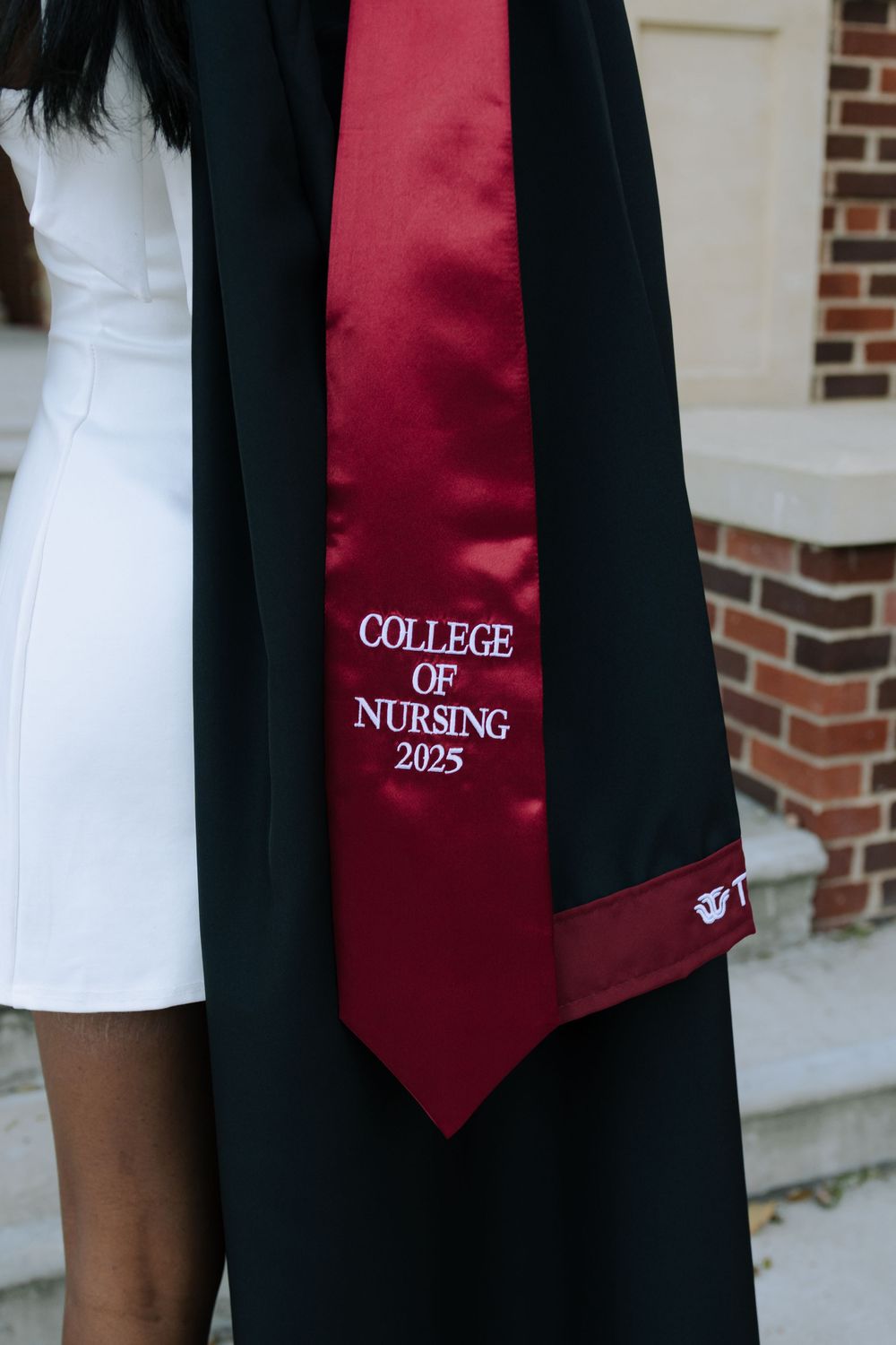 A close-up view of a burgundy graduation stole showing 'College of Nursing 2025' text.
