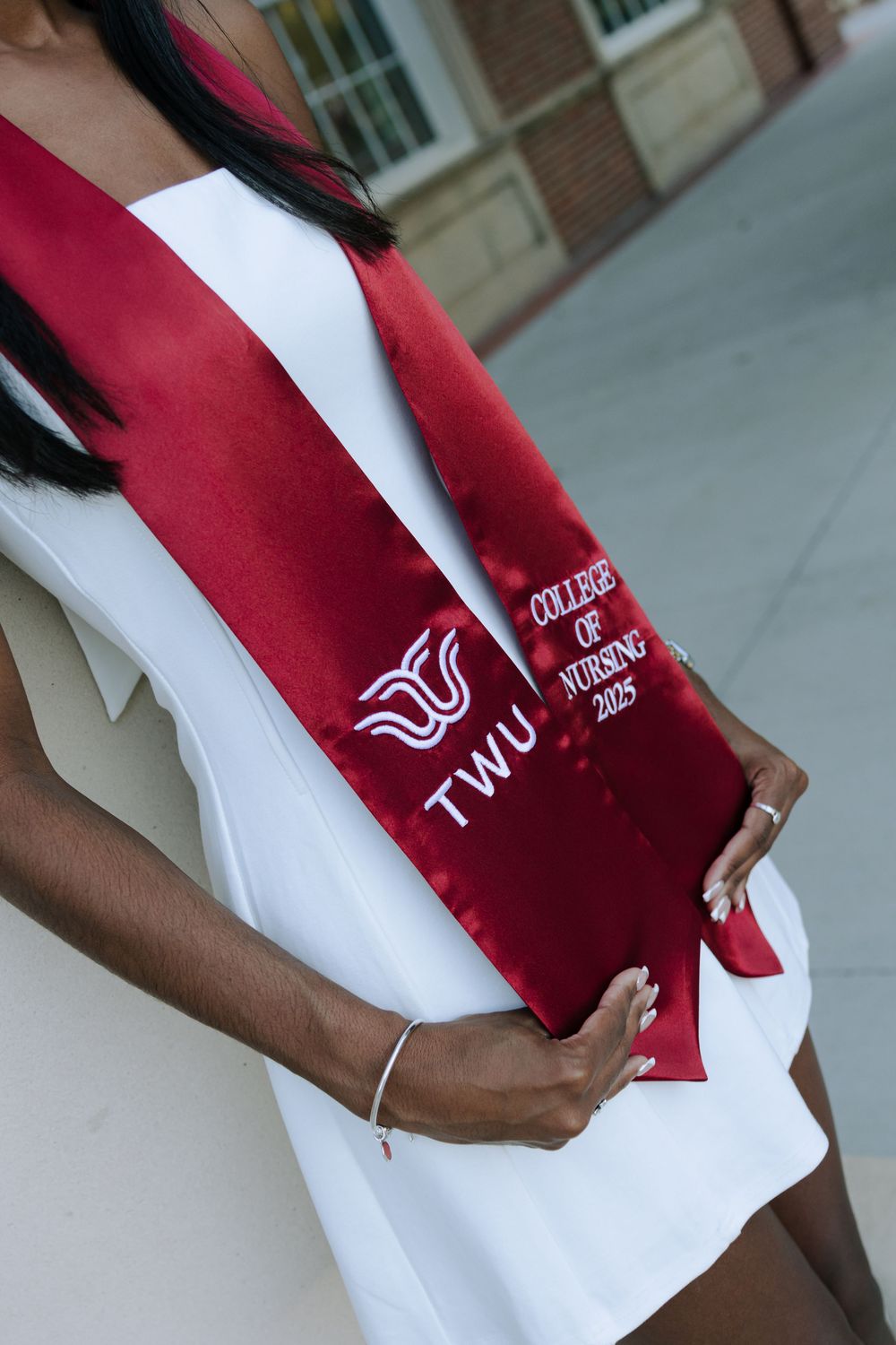 Close-up shots of a red and white TWU graduation stole with embroidered details.