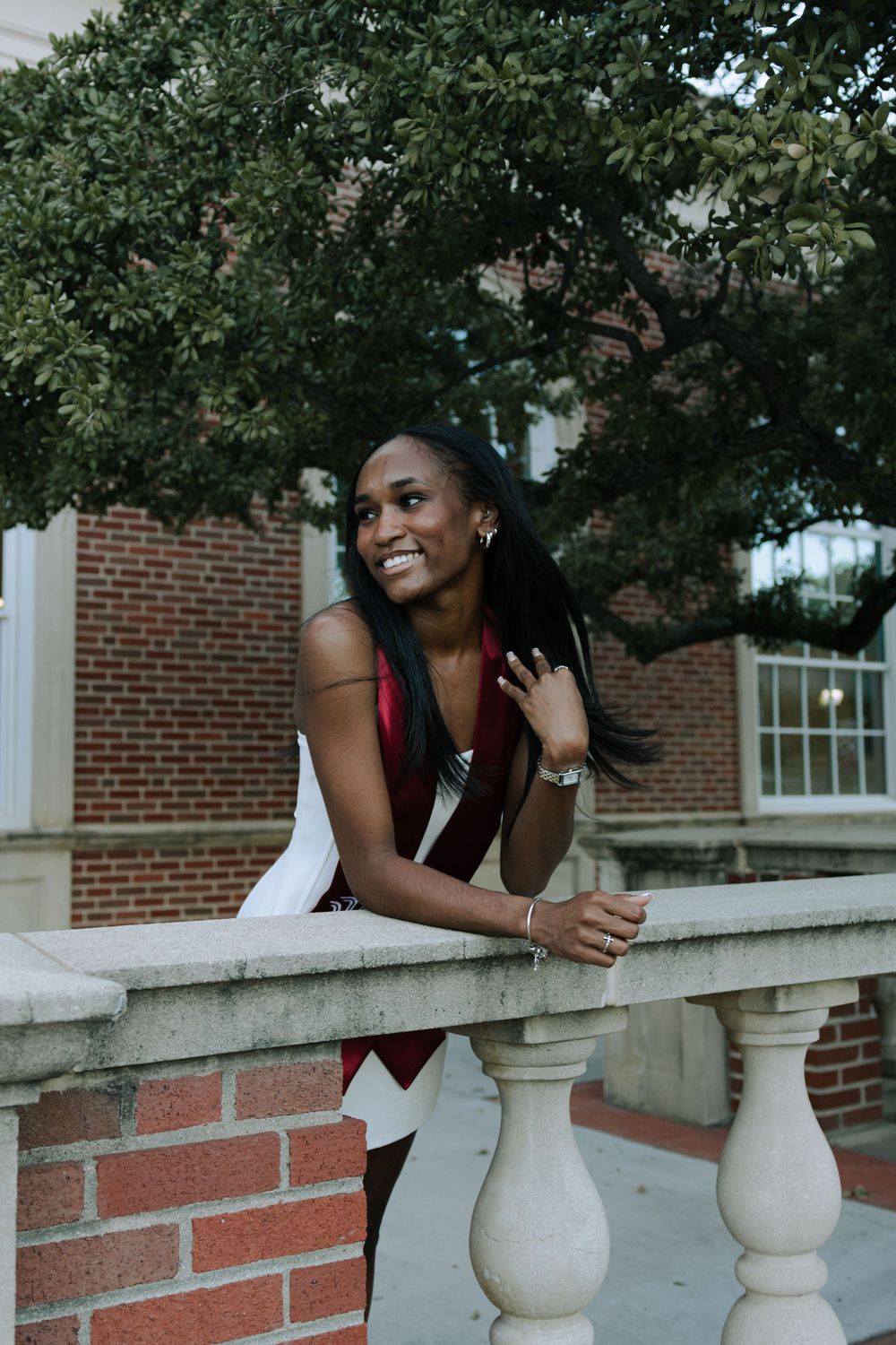 Outdoor portrait session with white brick columns and trees in the background.