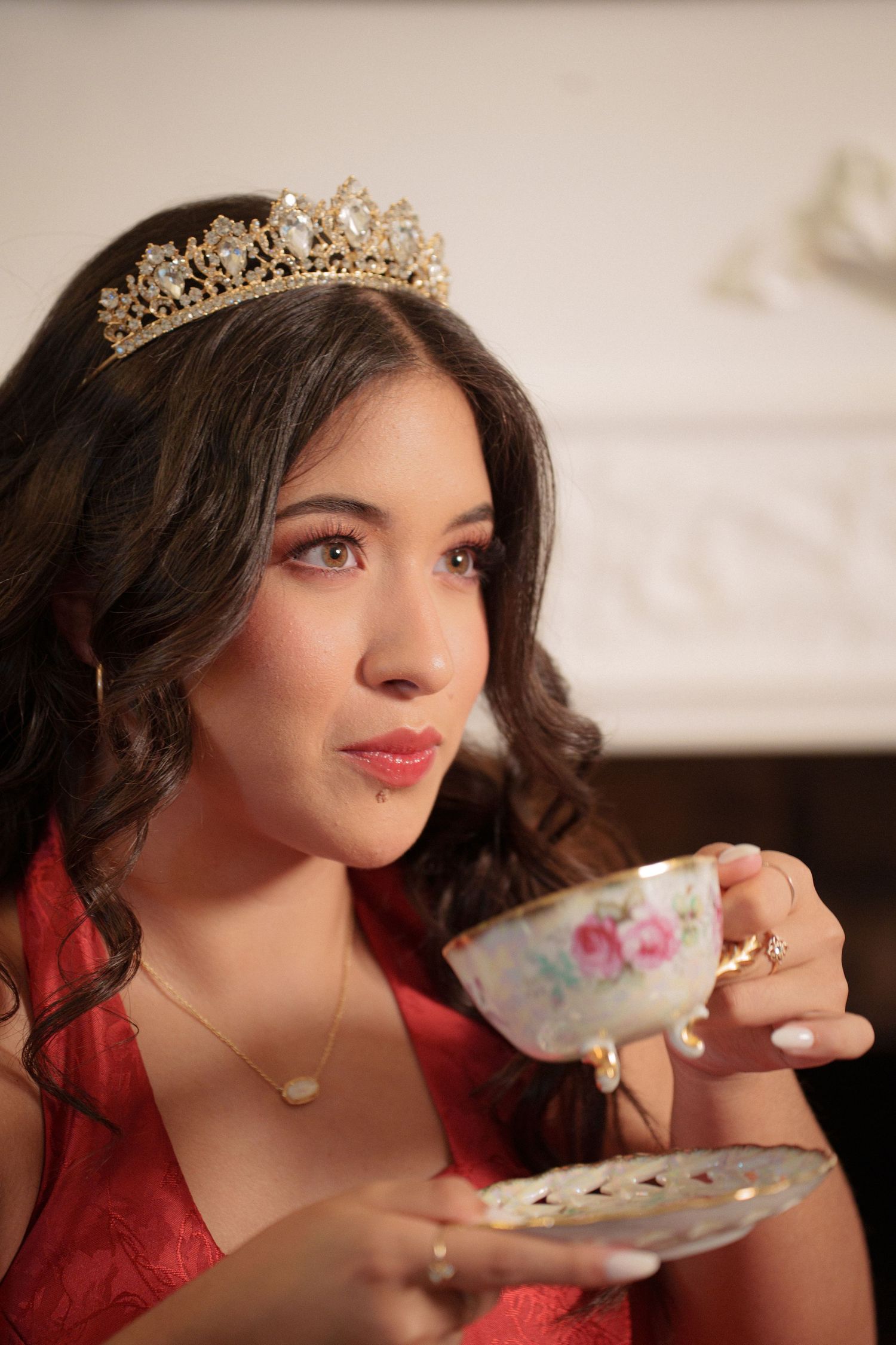 A delicate teacup and saucer being held in an elegant setting with decorative details.