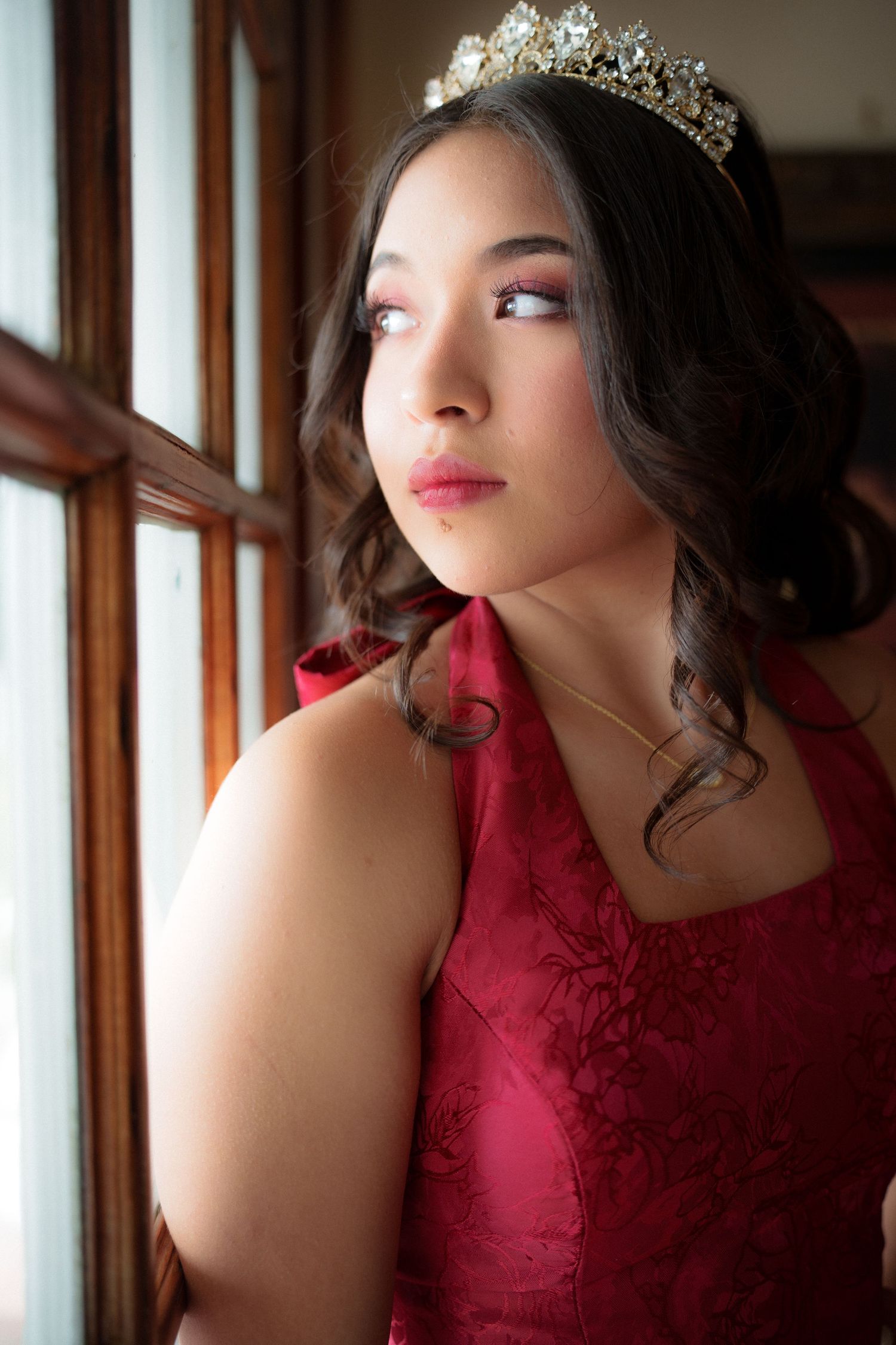 A glamorous red dress and tiara captured in an elegant portrait setting.