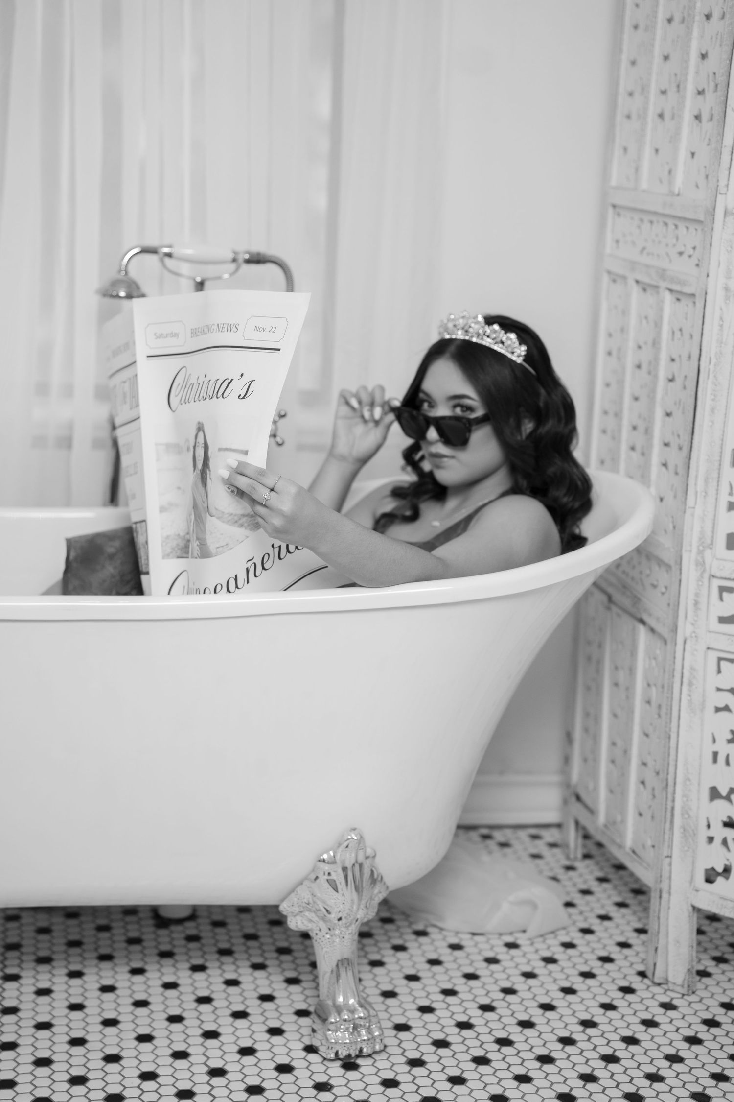Black and white photo of a vintage bathtub scene with invitation cards and classic decor.