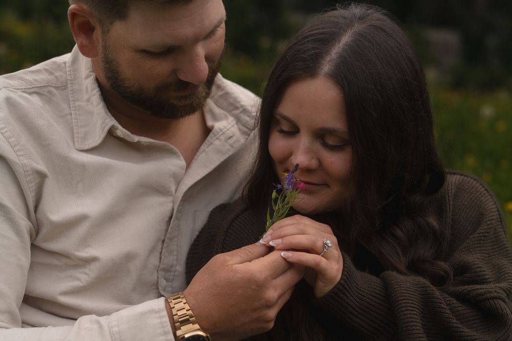 A couple embracing and sharing intimate moments in an outdoor setting while wearing casual attire.