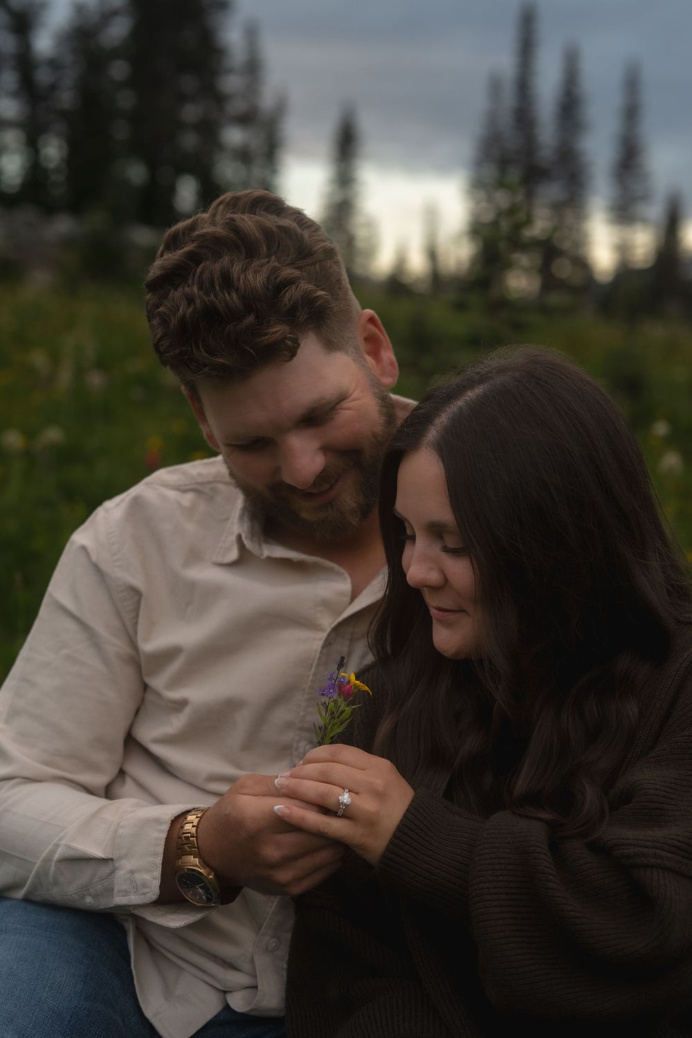 Couple shares intimate moments together outdoors at sunset among evergreen trees.