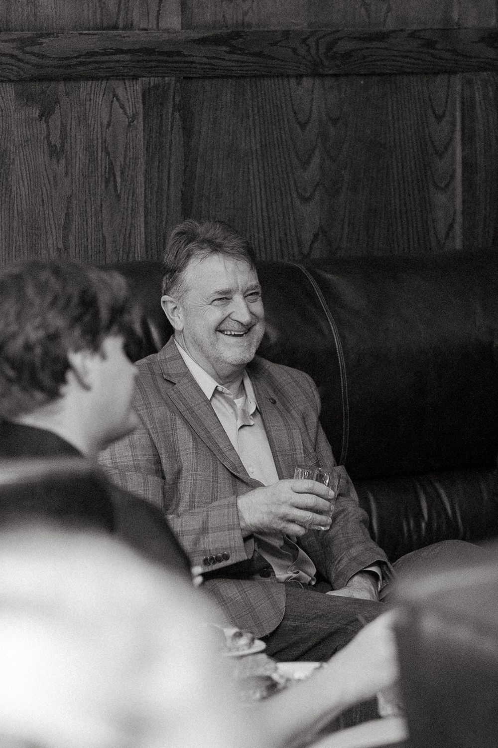 A series of vintage black and white photographs showing someone laughing while seated in what appears to be an interview setting.