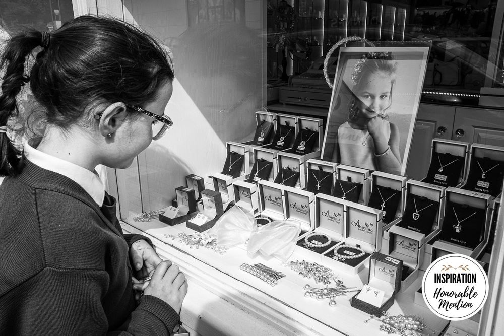 Black and white image showing display of vintage photographs in a gallery setting.
