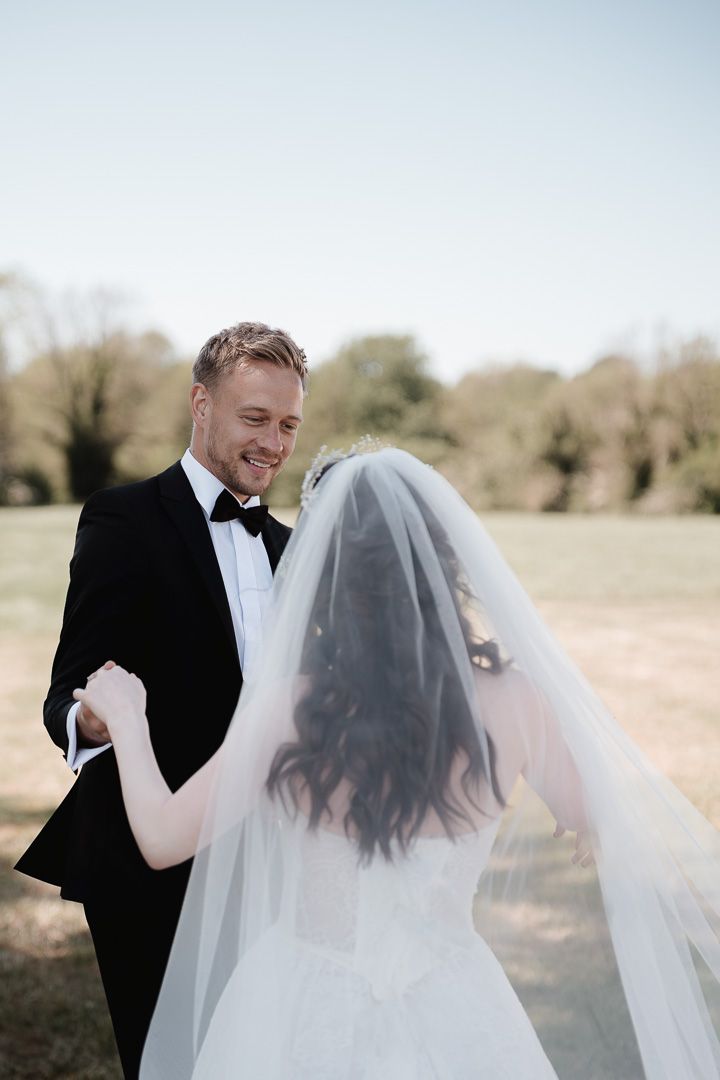 A couple shares a joyful moment on their wedding day in an outdoor setting with trees in the background.