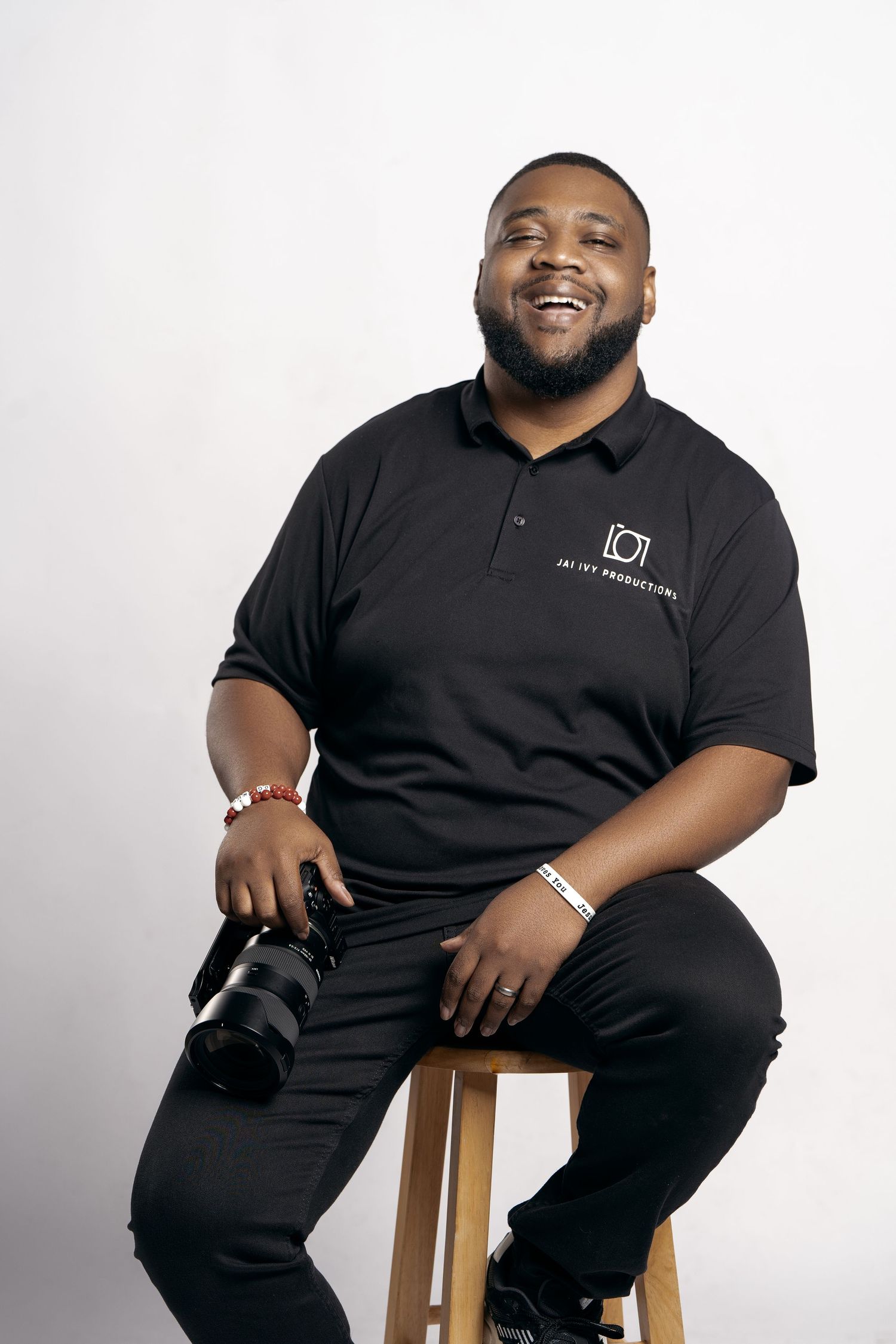 Professional studio portraits of a person in black attire seated on a wooden stool against a white backdrop.