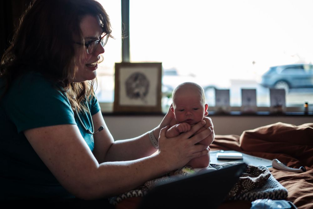 Midwife holding her newborn baby in home, sharing a tender bonding moment