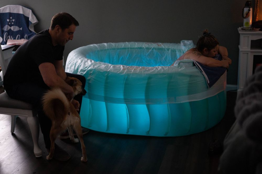 Mother in a birth pool, calmly laboring and embracing the soothing water during childbirth, surrounded by a peaceful and supportive space