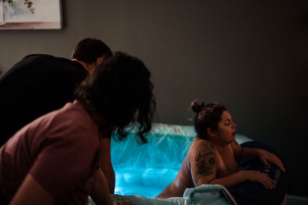 Mother laboring in a home birth pool in East Tennessee, surrounded by a serene and peaceful environment, embracing the natural process of ch