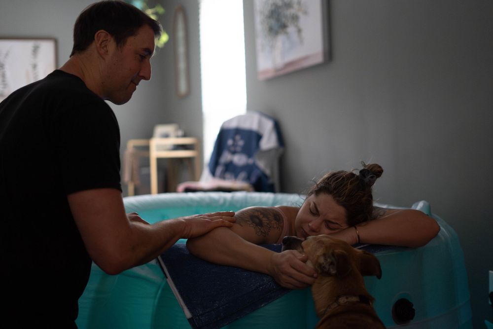 Husband lovingly supporting his wife during their home birth, offering comfort and encouragement as they share this transformative