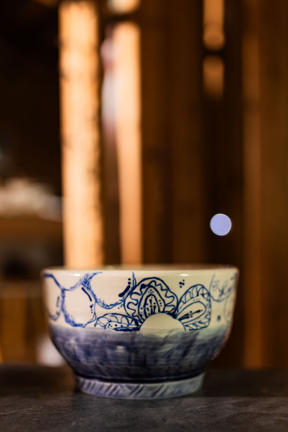 Artisan blue and white ceramic bowl with intricate floral motifs on a dark surface.