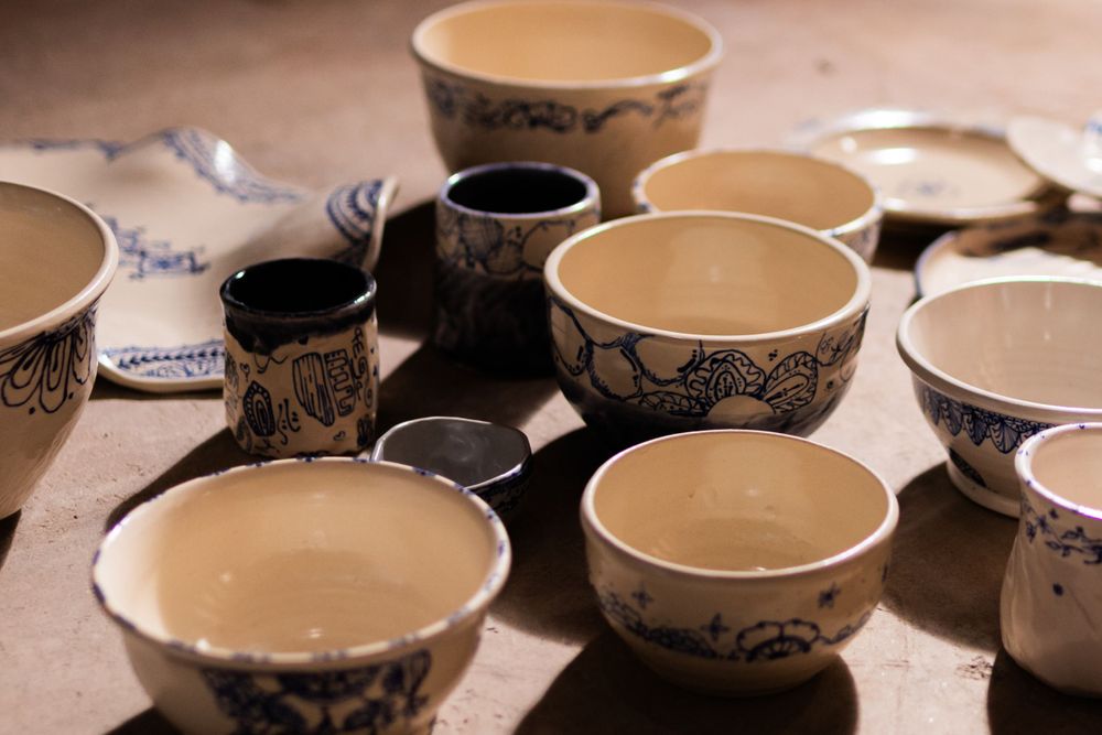 Multiple handmade ceramic bowls with blue floral patterns in various sizes displayed on wooden surface.