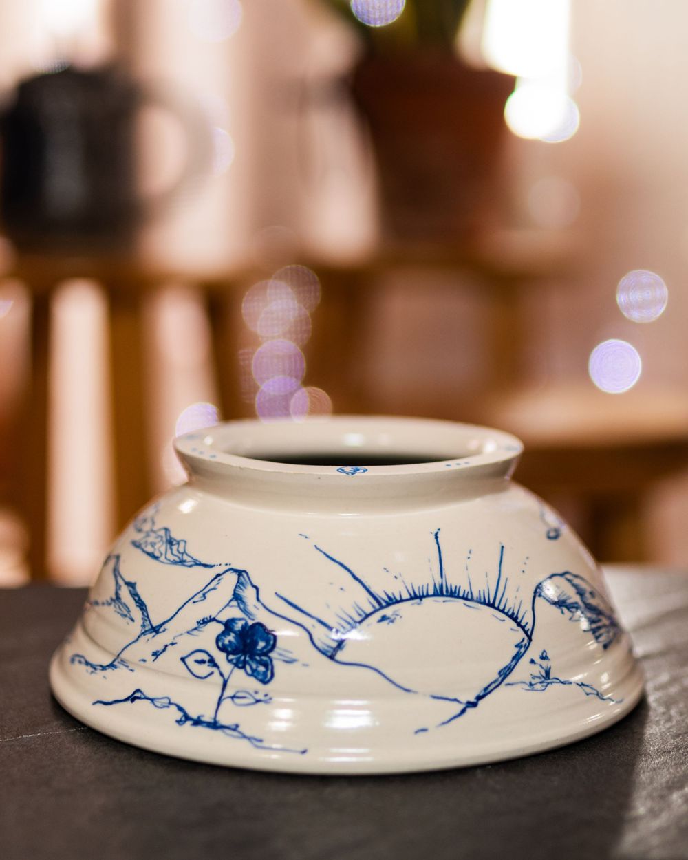 White ceramic bowl with blue hand-painted sleeping cat design on dark surface.