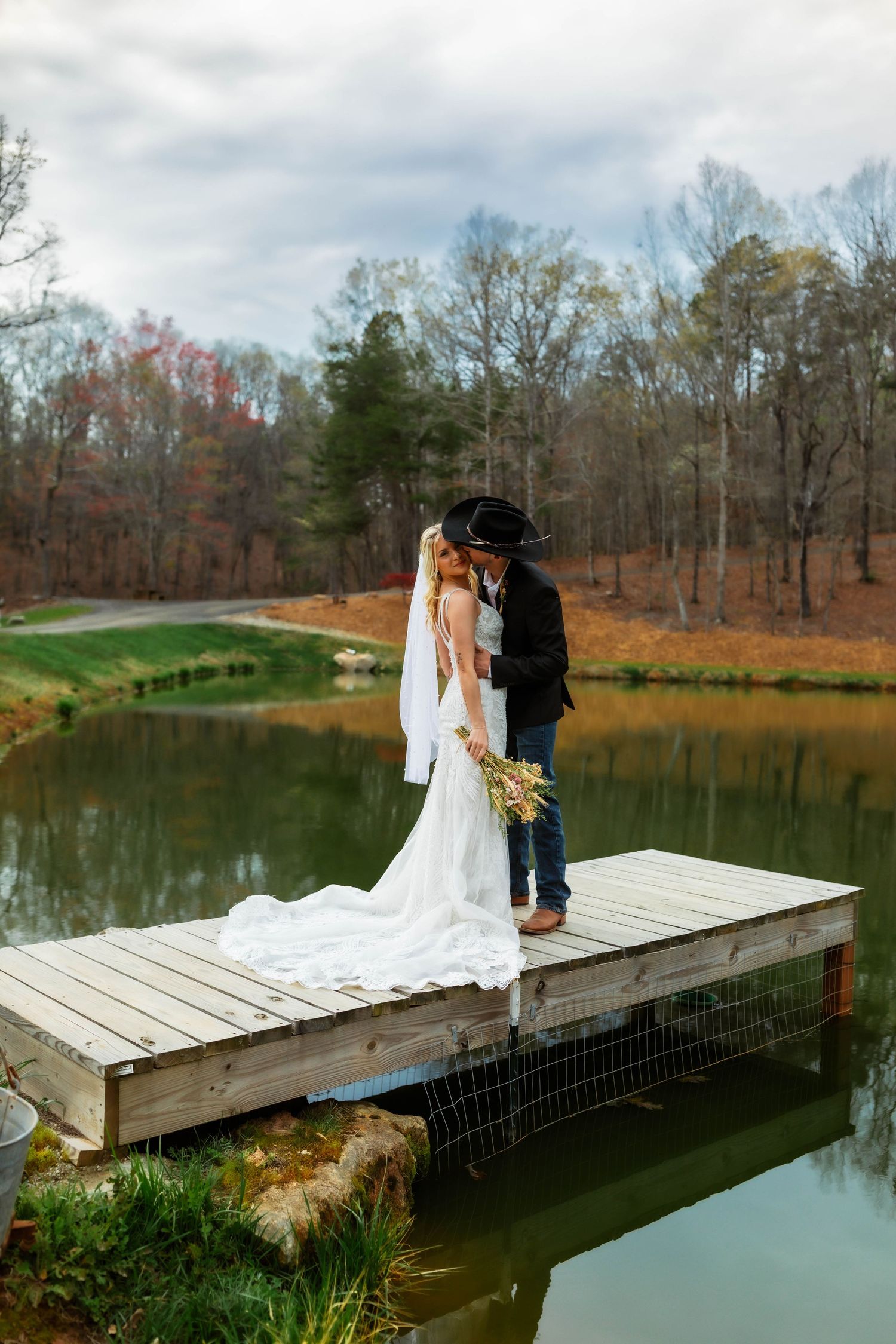 A romantic couple embraces in a field during golden hour sunset with autumn leaves on the ground.