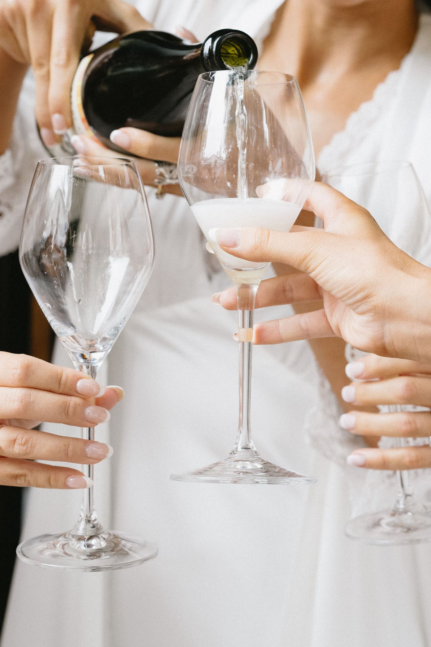 Hands pouring champagne into elegant crystal glasses for wedding celebration toast.