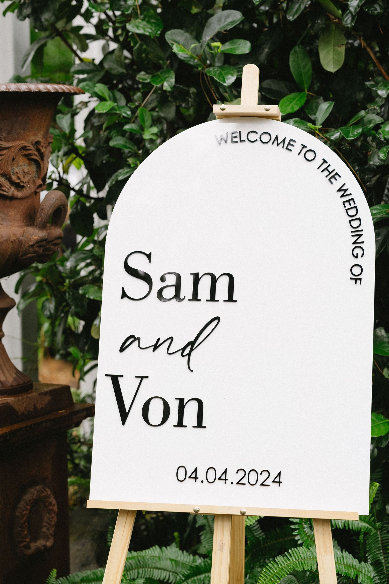 White wedding welcome sign on easel displaying 'Sam and Von' with wedding date.